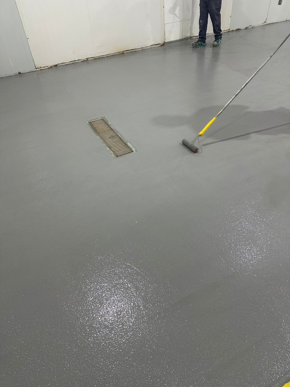 Aplicação do acabamento de uretano com rolo sobre o piso industrial