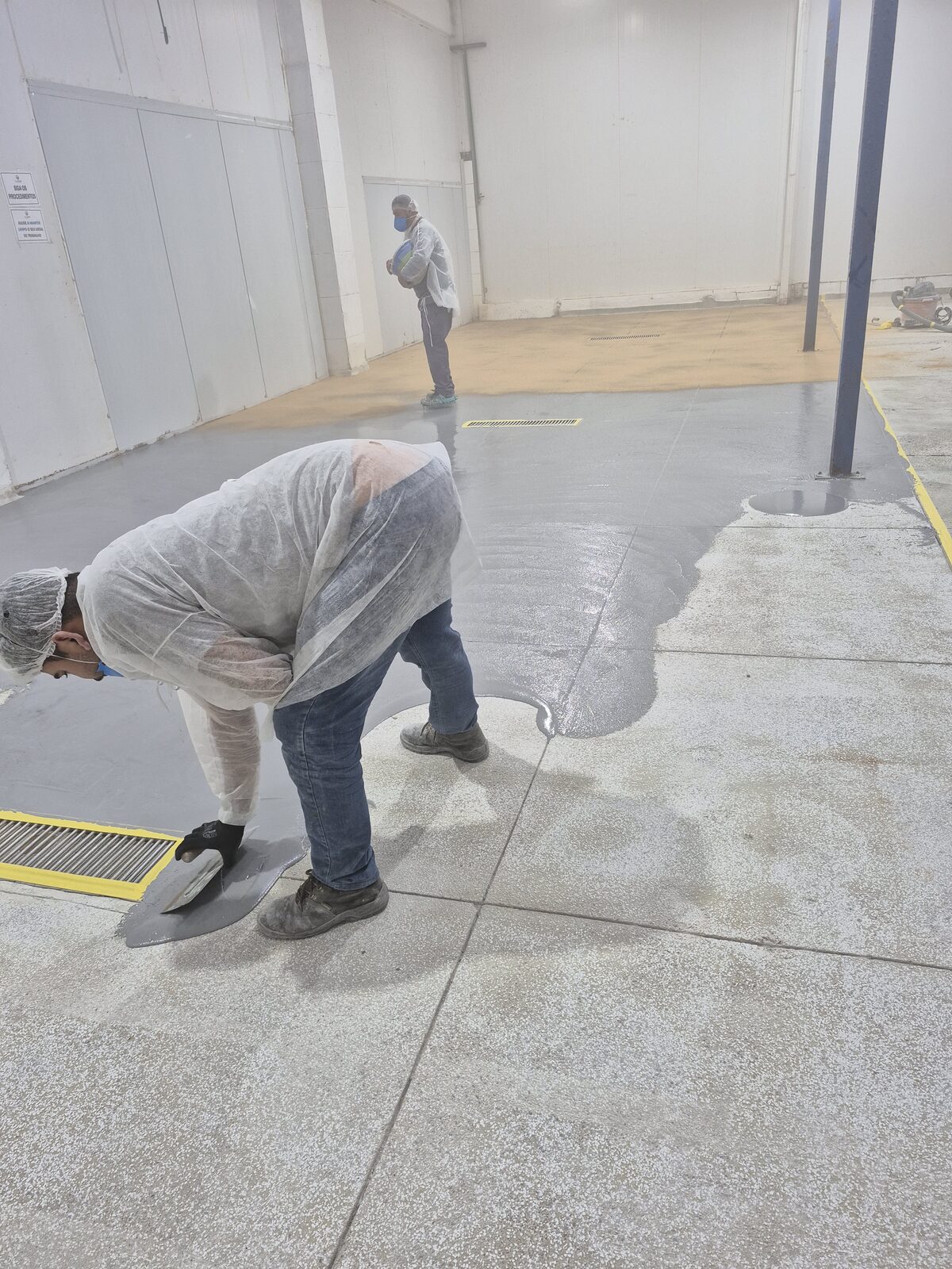 Operador desempenando a argamassa de uretano no piso